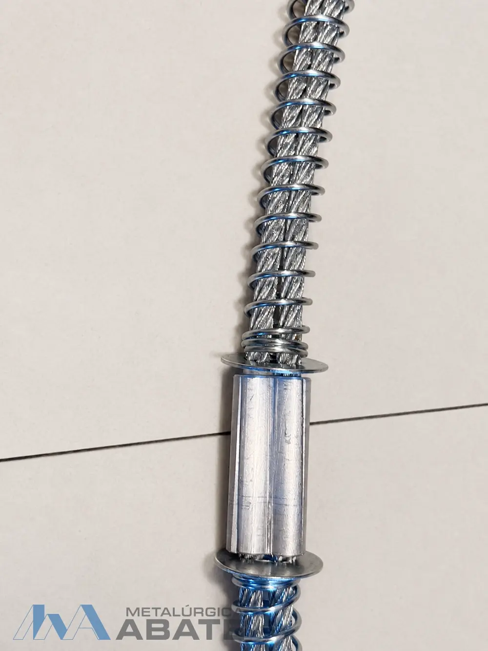 Detalle del cable, resorte exterior y unión central de una eslinga antilátigo
